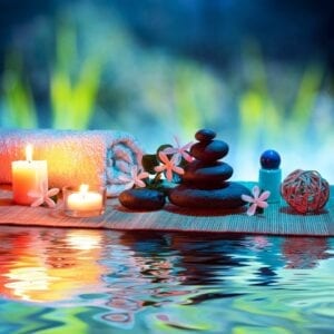 A candle lit with candles and rocks on the water.