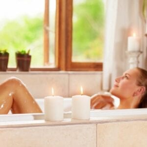 A woman laying in the bathtub with candles.