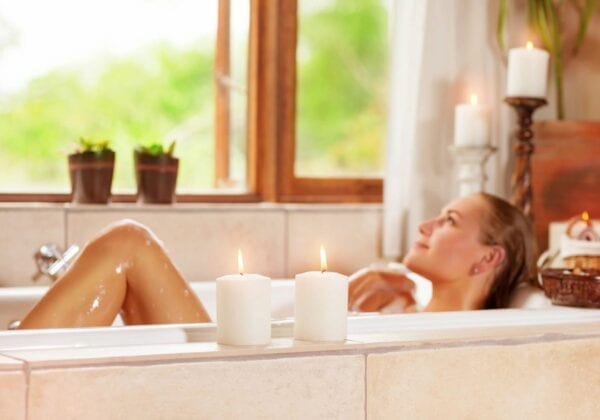 A woman laying in the bathtub with candles.