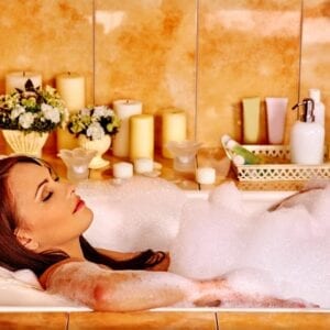 A woman laying in the bathtub with foam on her body.