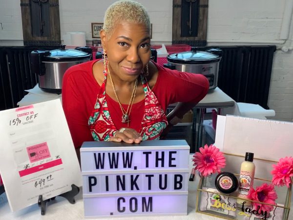 A woman sitting in front of some pink tub products.