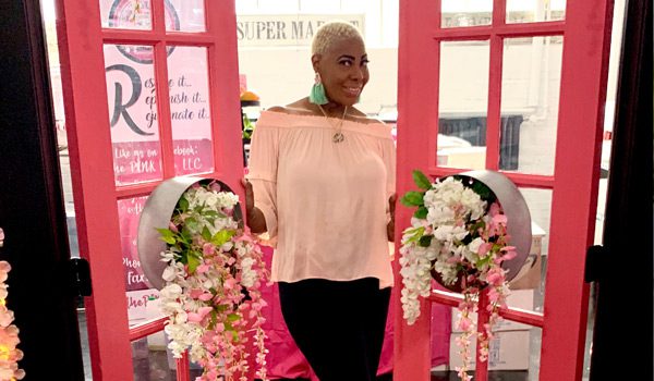 A woman standing in front of pink doors.