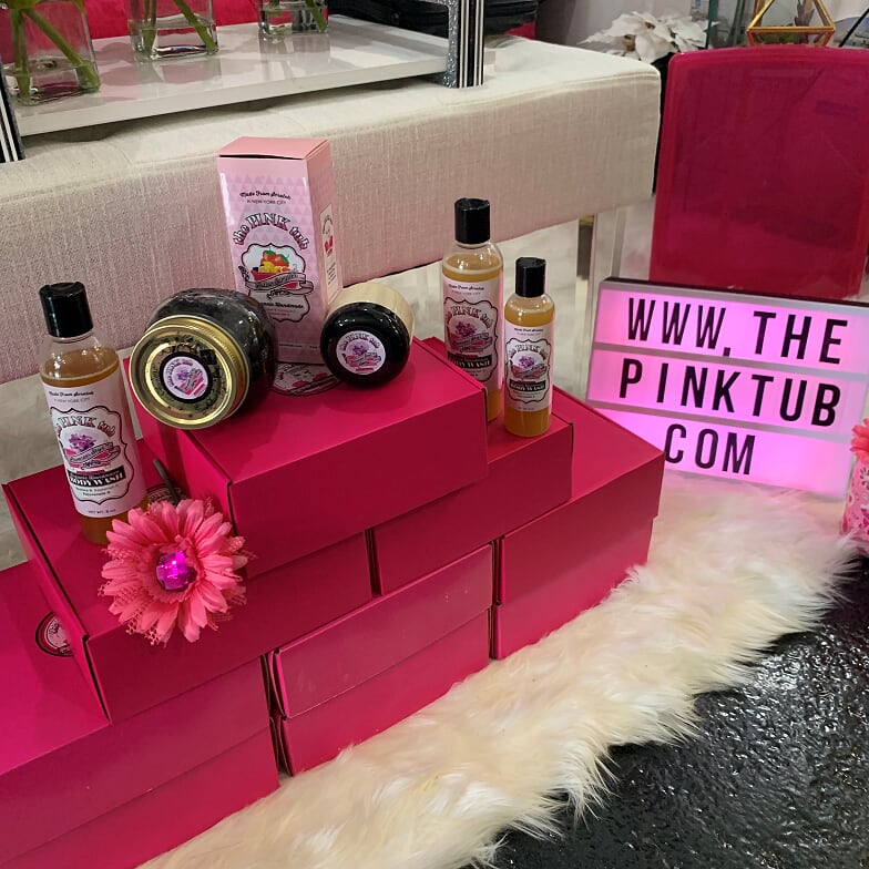 A display of pink boxes with products on top.